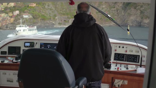 Skipper on captain bridge during sea walk on background green hill on coast Italy