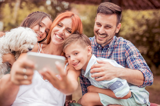 Smiling young family taking selfie in the park.