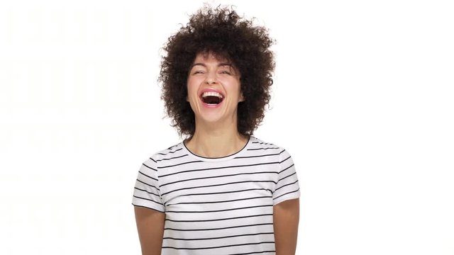 portrait of amazing lovely mixed-race female wearing stripped t-shirt bursting with laughter expressing happiness and joy being isolated over white background in studio. Concept of emotions