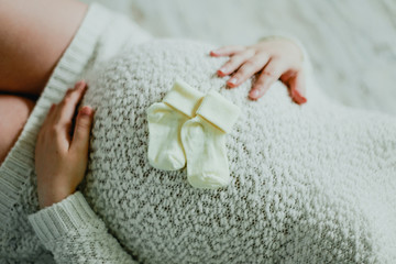 Little socks the unborn child in the hands of a pregnant woman