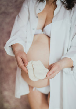 Little socks the unborn child in the hands of a pregnant woman