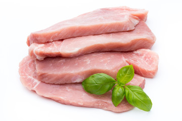 Fresh pork fillet with basil on a white background.