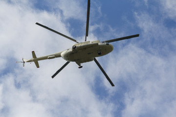 Fototapeta na wymiar Helicopter flies against a blue sky background. Transport