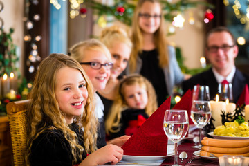 German Mother, father, children celebrating Christmas eve with traditional dinner Wiener sausages and potato salad 