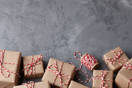 Christmas gift or present boxes wrapped in kraft paper with striped baker's twine string on textured stone background, copy space