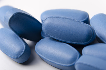 close up of blue pills or tablets over a white background.