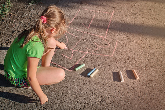 Girl Hopping On A Hopscotch Game Painted On Pavement.