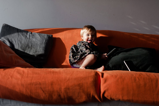girl on an orange couch with remote control