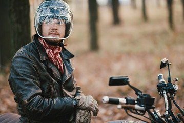 Man and old custom cafe-racer Motorcycle on forest 