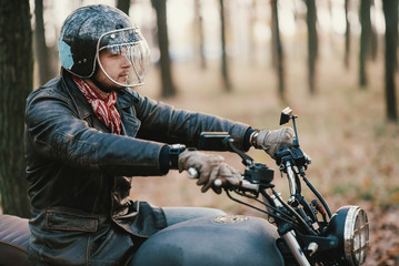 Man and old custom cafe-racer Motorcycle on forest 