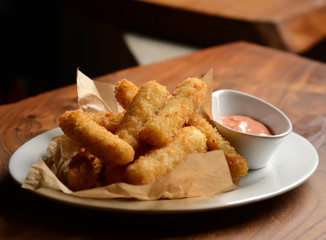 Delicious breaded mozzarella cheese sticks stack with hand pour marinara dipping sauce