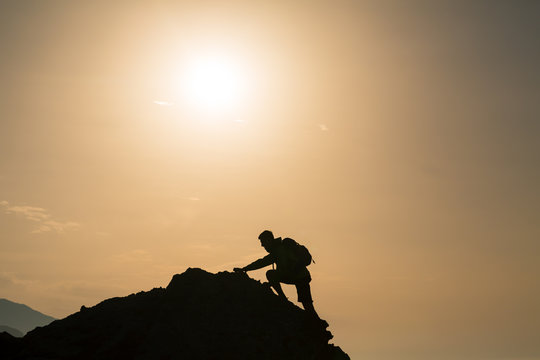 Climbing hiking silhouette in mountains over summer sunrise