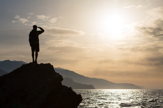 Hiking silhouette backpacker, man looking at ocean