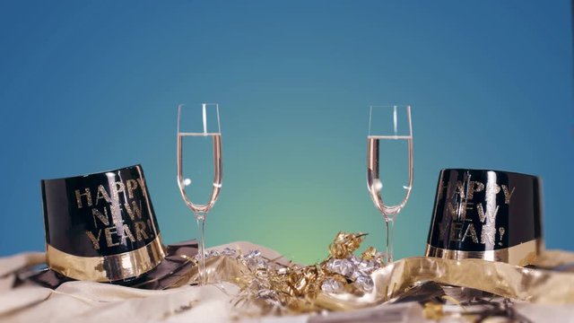 New Years Eve Table Scene with Blue Background. a table scene for New Years Eve with two champagne glasses and hats with ribbon on a blue background