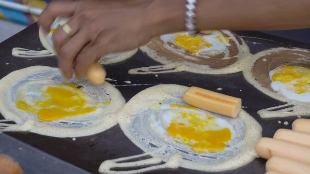 Preparing street food in bangkok Thailand - fried eggs with hot dog and dough