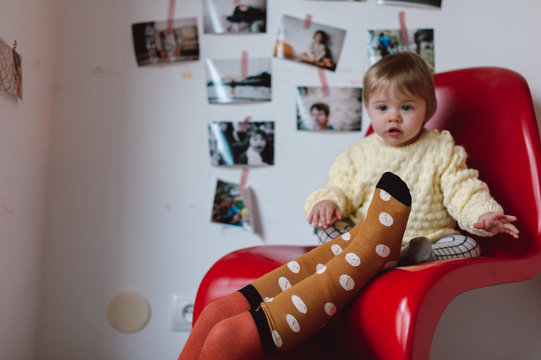 baby on a red chair and sister's legs