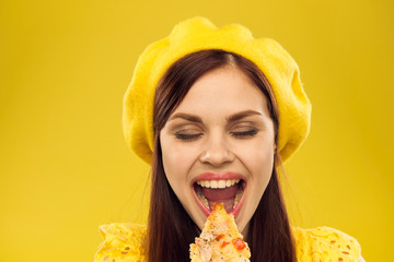 woman on a yellow background eating pizza