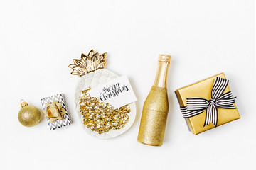 Gold plate-pineapple with sparkles of confetti and blank card, Gift boxes,  Champagne bottle in Gold colors. Flat lay, top view
