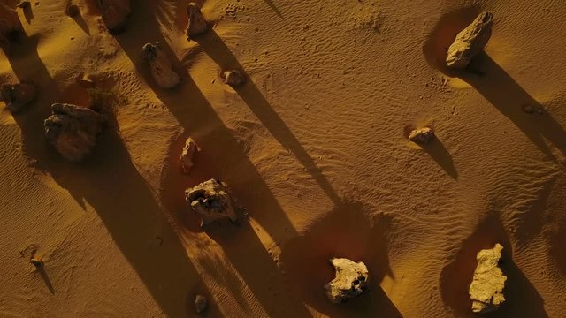 Rocks throwing shadows on sand, aerial view from above