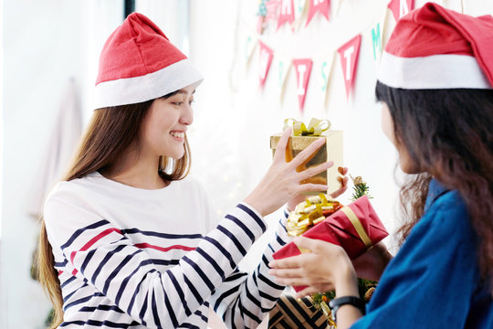 Two asian women holding gift box with happiness in Christmas party, friends Christmas party celebration