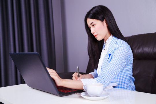 business woman working with laptop computer and writes a journal on the notebook