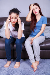 two worried woman on sofa at home