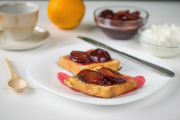 Two pieces of fried French bread on a white plate on a wooden table.