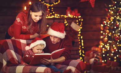 Merry Christmas! family mother father and baby read book near tree