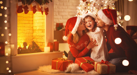 Merry Christmas! happy family mother father and child with gifts near tree