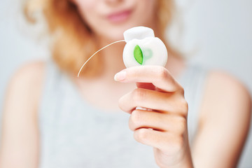 A young girl holding a dental floss on white background