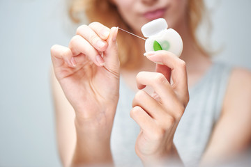 A young girl holding a dental floss on white background