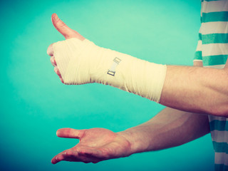 Man with bandaged hand showing thumb up.