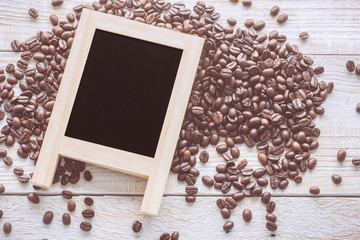 Blank blackboard with coffee beans on wood background. copyspace for advertising