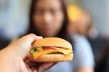 Burger in young man hands select focus blur background, Young man holds burger with hands, Close-up burger with blur background