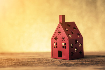 Obraz na płótnie Canvas red metal house model with golden bokeh background with free copyspace for your text