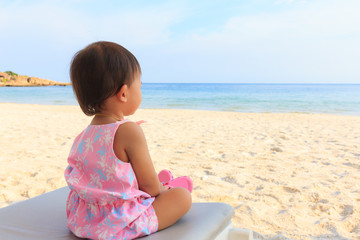 Asian cute baby girl siting on beach bed.