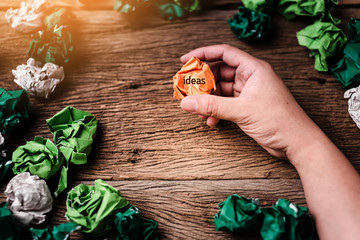 hand pick orange color  trash paper with background of old wooden table creativity ideas concept