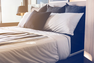 Bed maid-up with clean white pillows and bed sheets in beauty room. Close-up. Lens flair in sunlight.