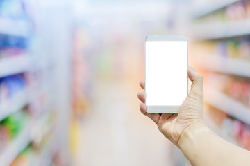blur image background of supermarket in shopping mall with hand hold blank screen smartphone for your text