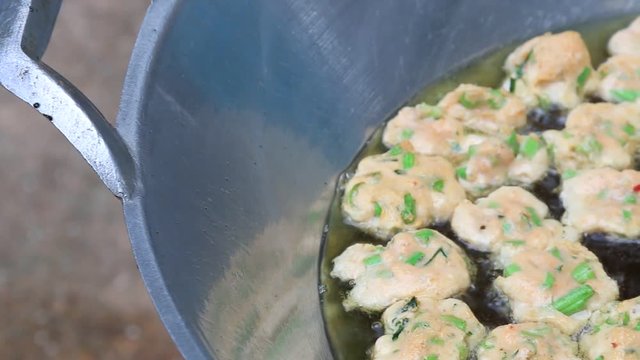 Thai fried fish-paste balls with hot oil in big pan, Thai street food.