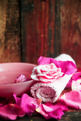 Spa settings with roses. Fresh roses and rose petals in a bowl of water and various items used in spa treatments