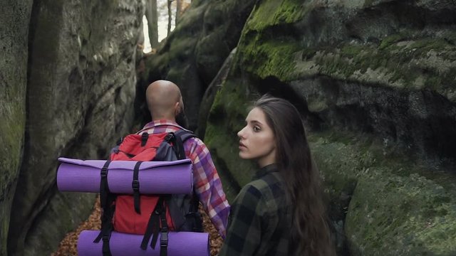 Close-up. Man and woman with a backpack walking along the path of a pedestrian path between the rocks during the sunny sunny autumn day