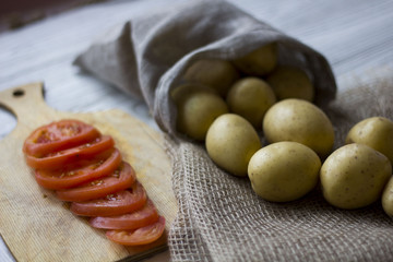 potatoes in the bag and sliced tomatoes on a wooden table