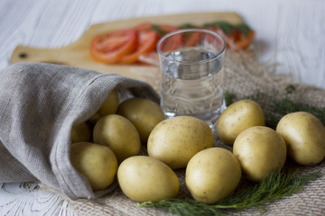 potatoes in the bag and sliced tomatoes and a glass of water on a wooden table