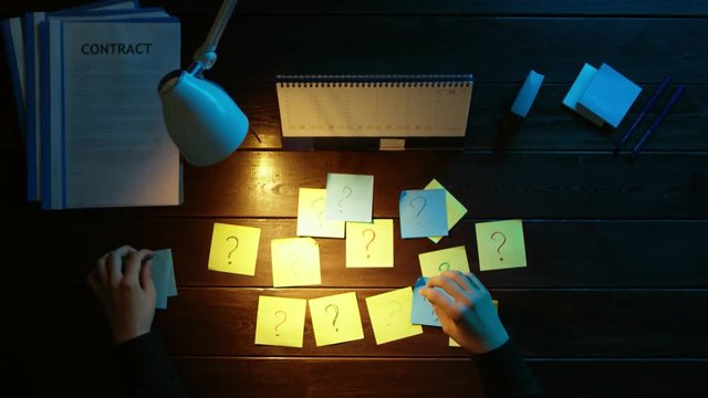 A man is sitting at an office desk and using a phone.