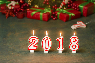 New Year 2018 background with 2018 illuminated candles placed with Christmas colorful decorations. Close up view with copy space.