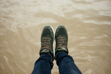 top view. foot of women wearing shoe, jeans stand on water surface are background. image for body, abstract, nature, travel, equipment, fashion, lifestyle concept