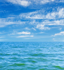 Plakat blue sea and sky with clouds over it