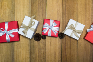 Obraz premium Red and white gift box on wood table with pine cone from top view. Christmas, New year, Valentine or Birthday concept. Still life.