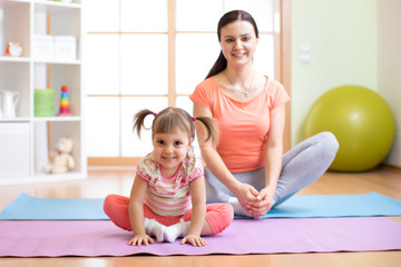 Mother and child daughter practicing yoga together at home. Sport and family concept